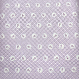 A close-up of a lavender-purple fabric with a repeating small white floral or paisley-like dot pattern, next to a pink patterned fabric strip.