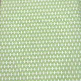 A close-up of a fabric or wallpaper pattern featuring a repeating white cross-hatch grid on a muted sage green background.