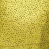 A close-up of a yellow fabric or wallpaper with a dense, small-scale dark floral or ditsy print pattern.