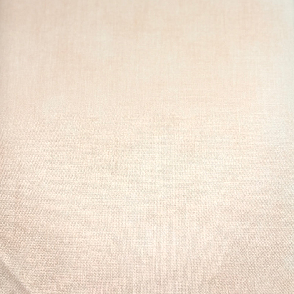A folded piece of light beige fabric with a subtle woven texture, resting on a dark wooden surface.