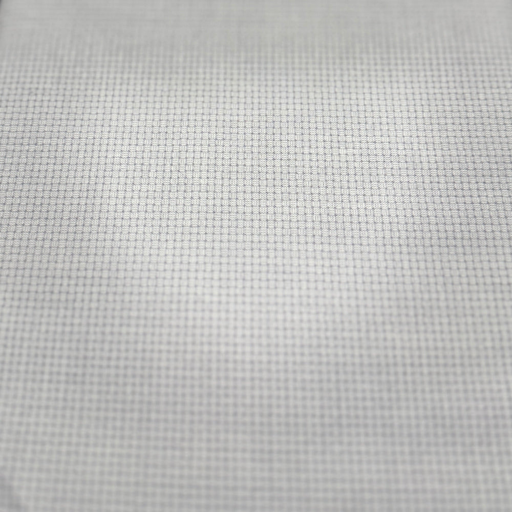 A close-up of a white woven fabric or mesh material with a fine grid texture, shown against a blurred background.