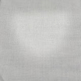 A close-up of a white woven fabric or mesh material with a fine grid texture, shown against a blurred background.