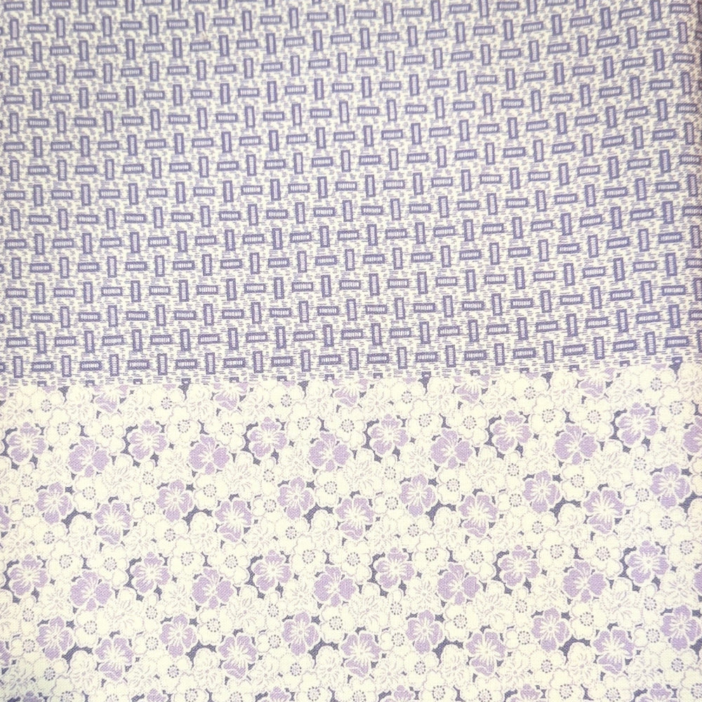 A folded piece of patterned fabric or paper showing two distinct printed sections: a top section with dense small gray-blue text and a bottom section with a repeating light purple floral or medallion pattern on a white background.