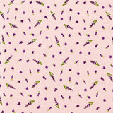 A close-up of a light pink fabric with a repeating pattern of small purple flowers and green leaves, laid flat next to other fabrics.