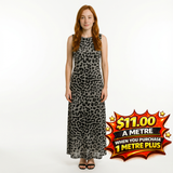 Woman in a long, sleeveless grey and black leopard print dress, standing on a white background.