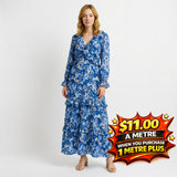 Woman in a blue floral tiered maxi dress with long sleeves and a ruffled V-neck.