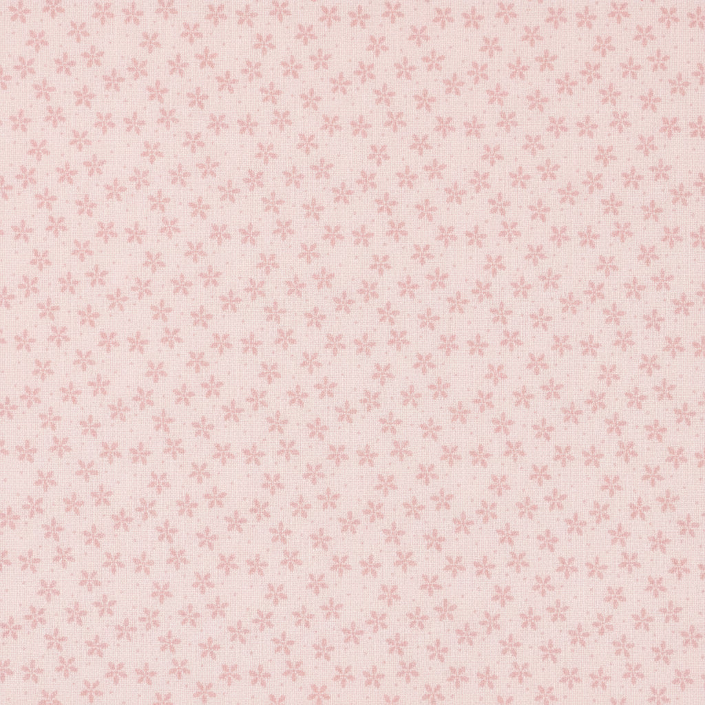 A close-up of a light pink fabric with a repeating small floral or starburst pattern in a slightly darker pink. A ruler and Modas logos are visible along the bottom edge, indicating the brand and scale.