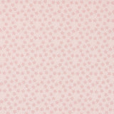 A close-up of a light pink fabric with a repeating small floral or starburst pattern in a slightly darker pink. A ruler and Modas logos are visible along the bottom edge, indicating the brand and scale.