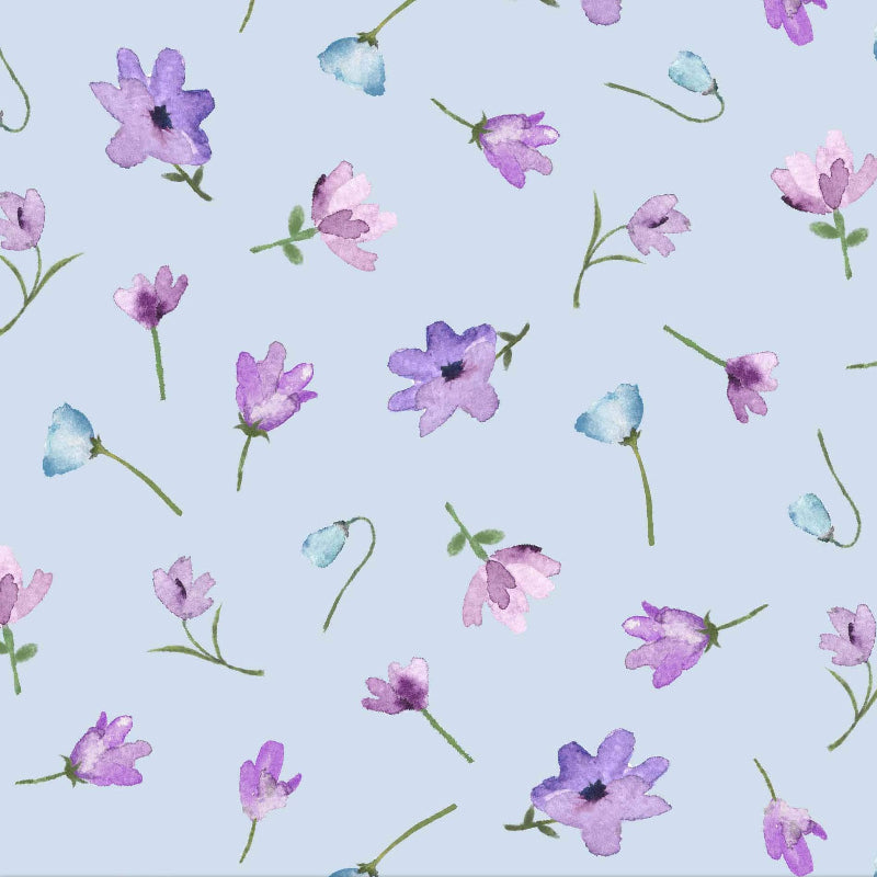 Light blue fabric with a repeating watercolor floral pattern of purple, pink, and blue flowers with green stems, shown with a wooden ruler at the bottom for scale.