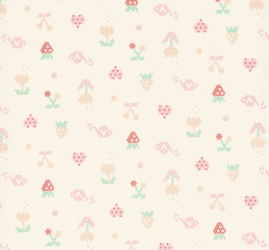 A repeating pattern of small cross-stitch style motifs on a warm cream background, including hearts, bows, flowers, and small geometric shapes in muted pink, peach, green, and tan.