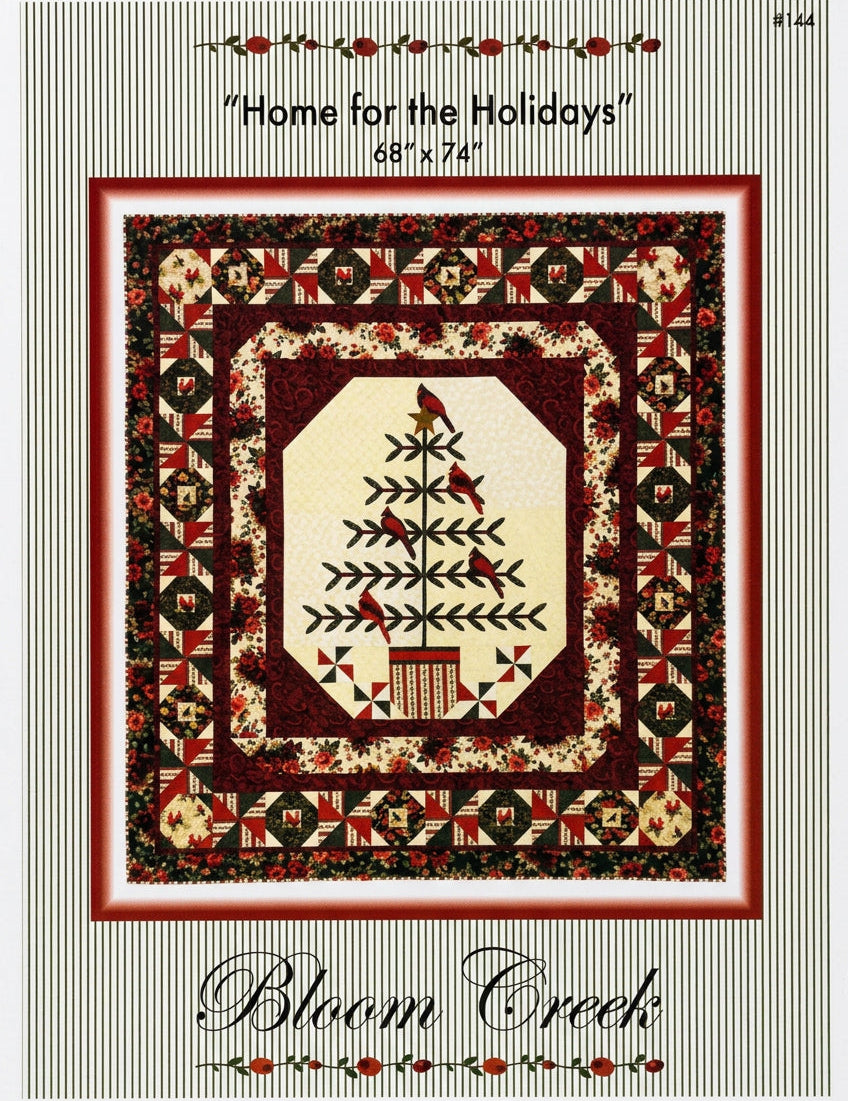 Bloom Creek 'Home for the Holidays' counted cross-stitch pattern in its original clear plastic packaging, featuring a festive quilted design with a central Christmas tree motif.