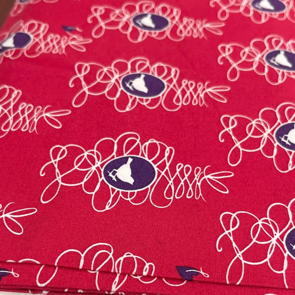 Red ironing board cover with floral pattern on a wooden surface, featuring Guttermann branding.