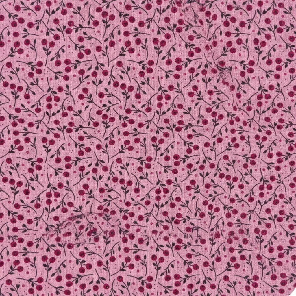 Pink fabric with a repeating cherry print pattern, featuring dark red cherries, pink stems, and green leaves, with a white ruler at the bottom edge showing measurements.